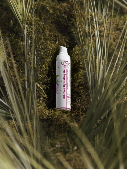 Gel hidratante oil-free em embalagem branca com detalhes rosa sobre musgo e plantas